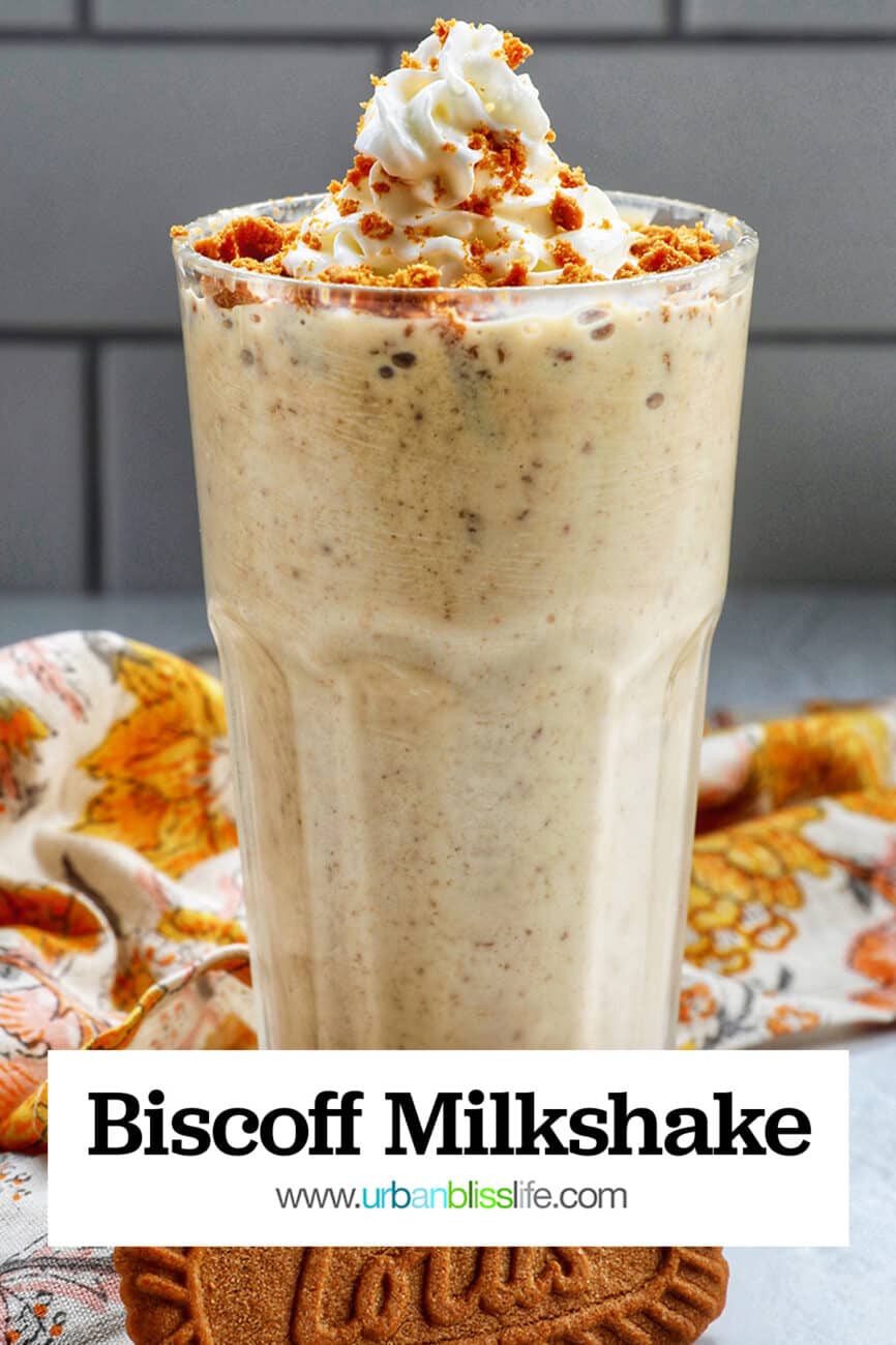 Biscoff Milkshake in a milkshake glass with a yellow floral kitchen linen and biscoff cookie.
