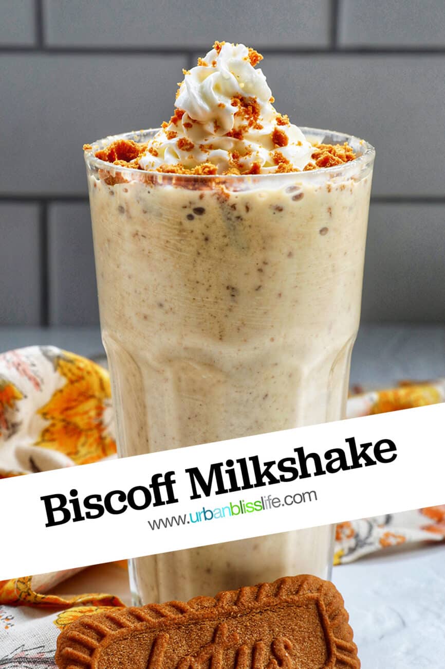 Biscoff Milkshake in a milkshake glass with a yellow floral kitchen linen and biscoff cookie.