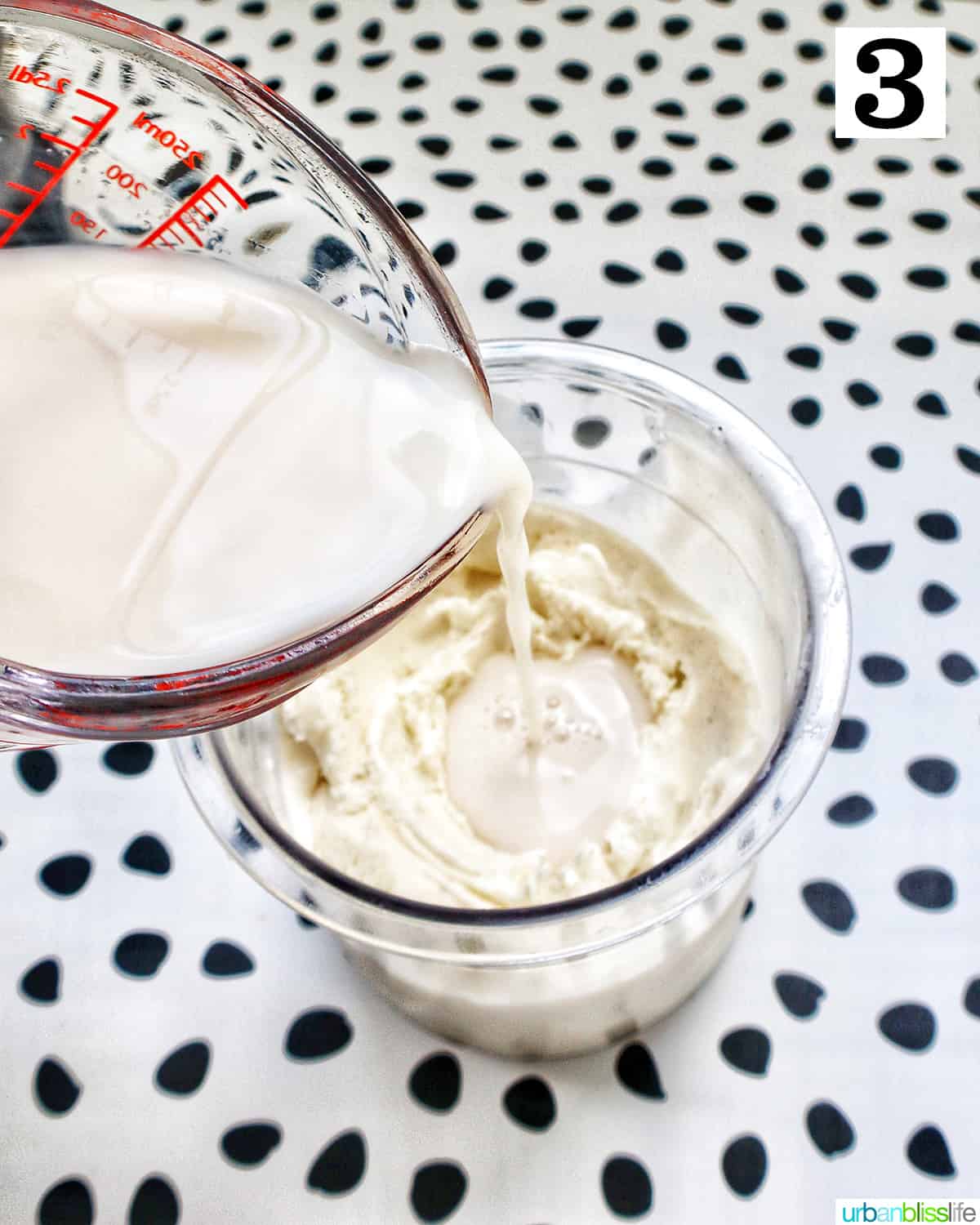 pouring milk into a Ninja Creami container with vanilla ice cream and a spoon.