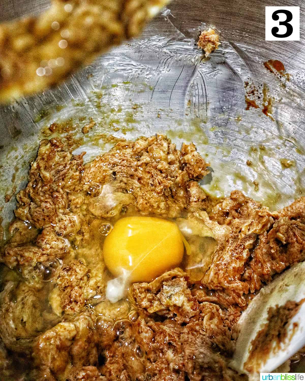 adding an egg to the coffee walnut cake batter in a stand mixer.