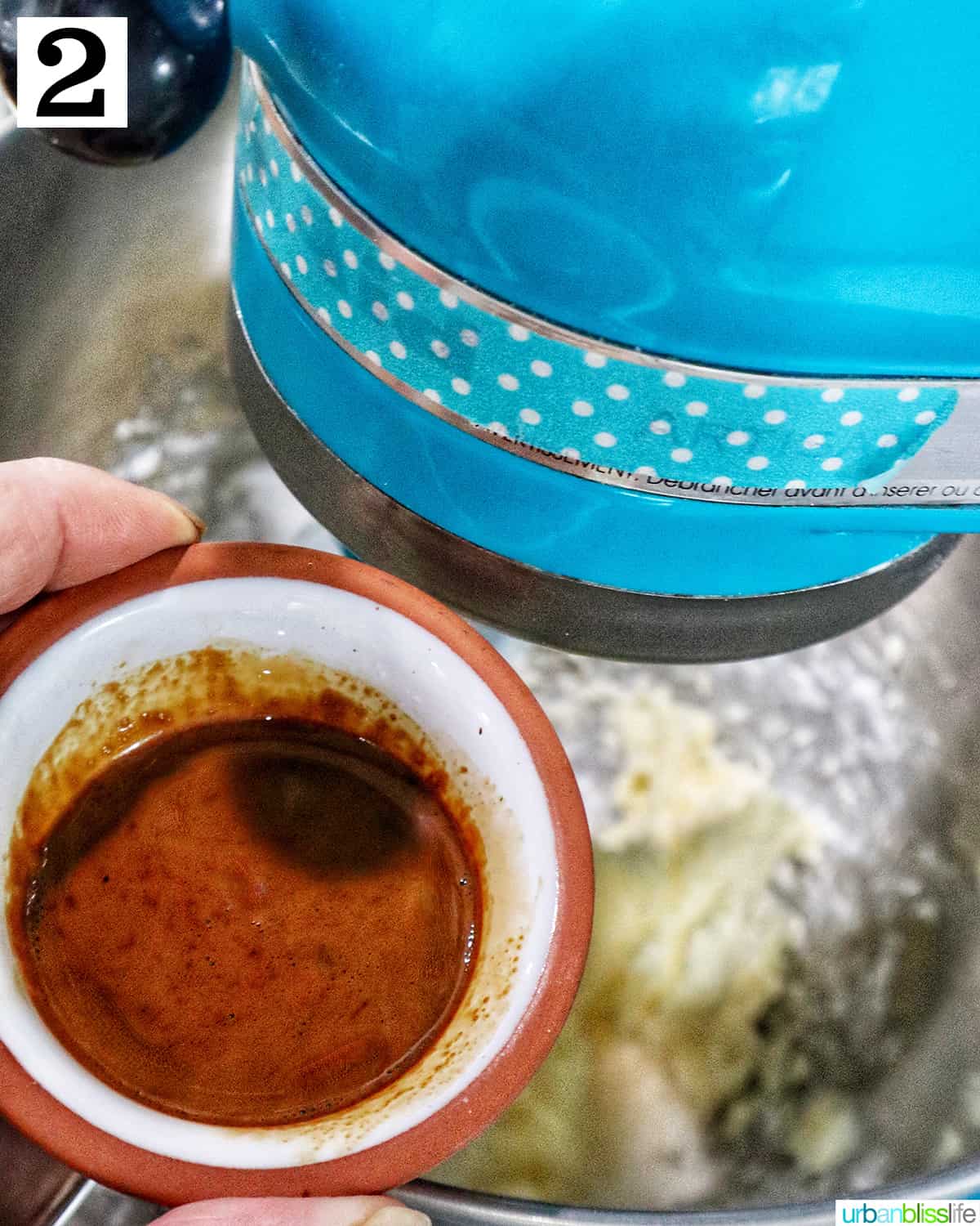 adding instant coffee to coffee buttercream frosting in a stand mixer.