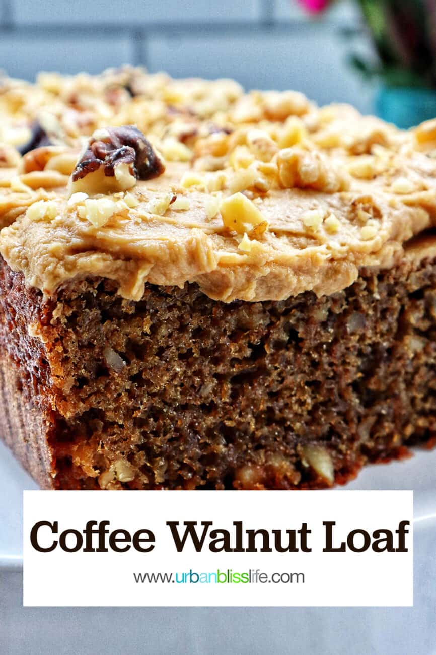 A coffee walnut loaf cake with coffee buttercream frosting on a white pedestal.