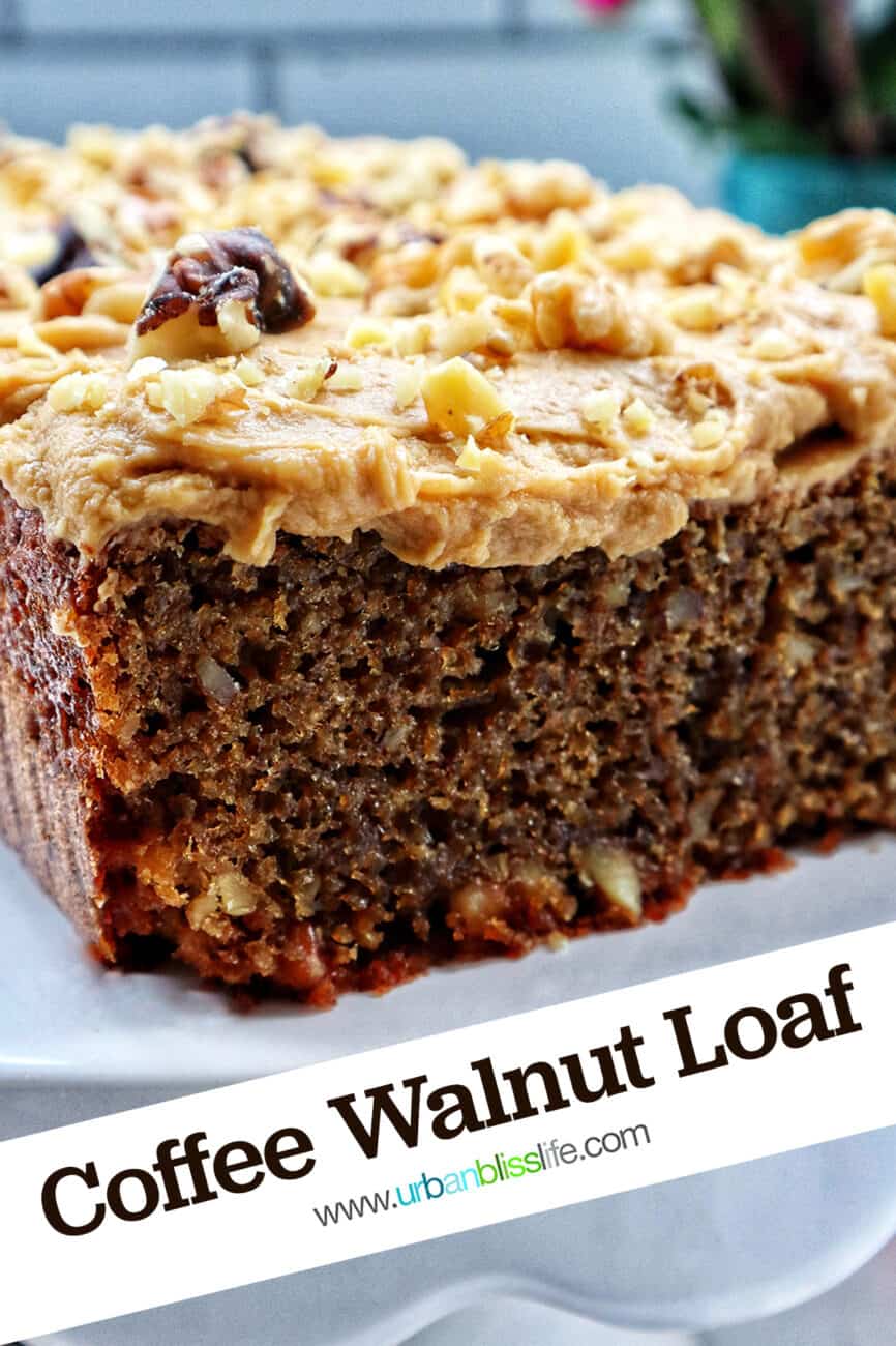 A coffee walnut loaf cake with coffee buttercream frosting on a white pedestal.