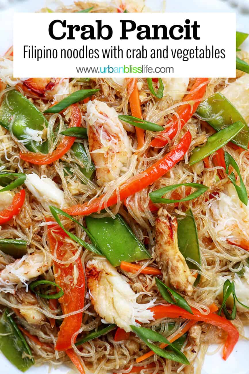 crab pancit filipino noodles in a large bowl, with slices veggies and chunks of crab meat.