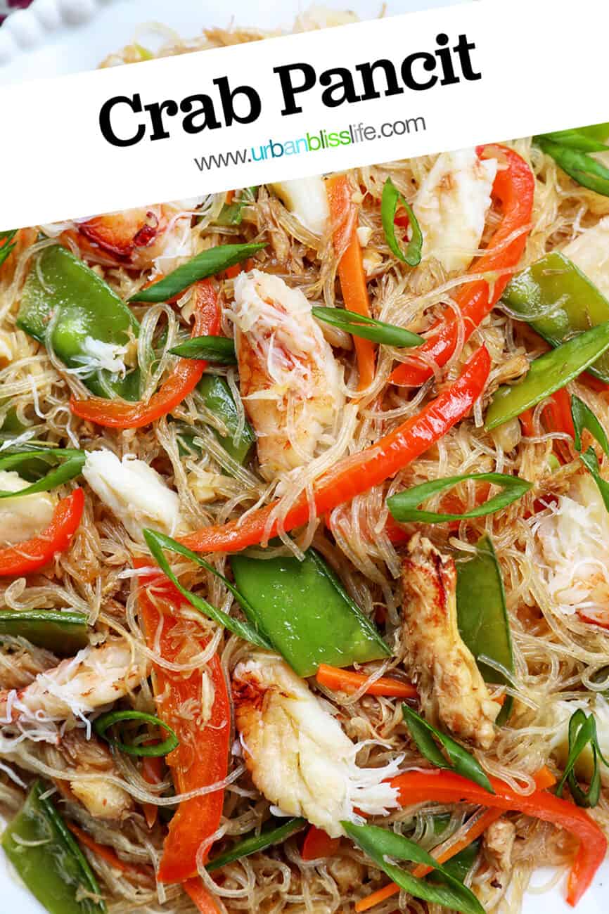 crab pancit filipino noodles in a large bowl, with slices veggies and chunks of crab meat.