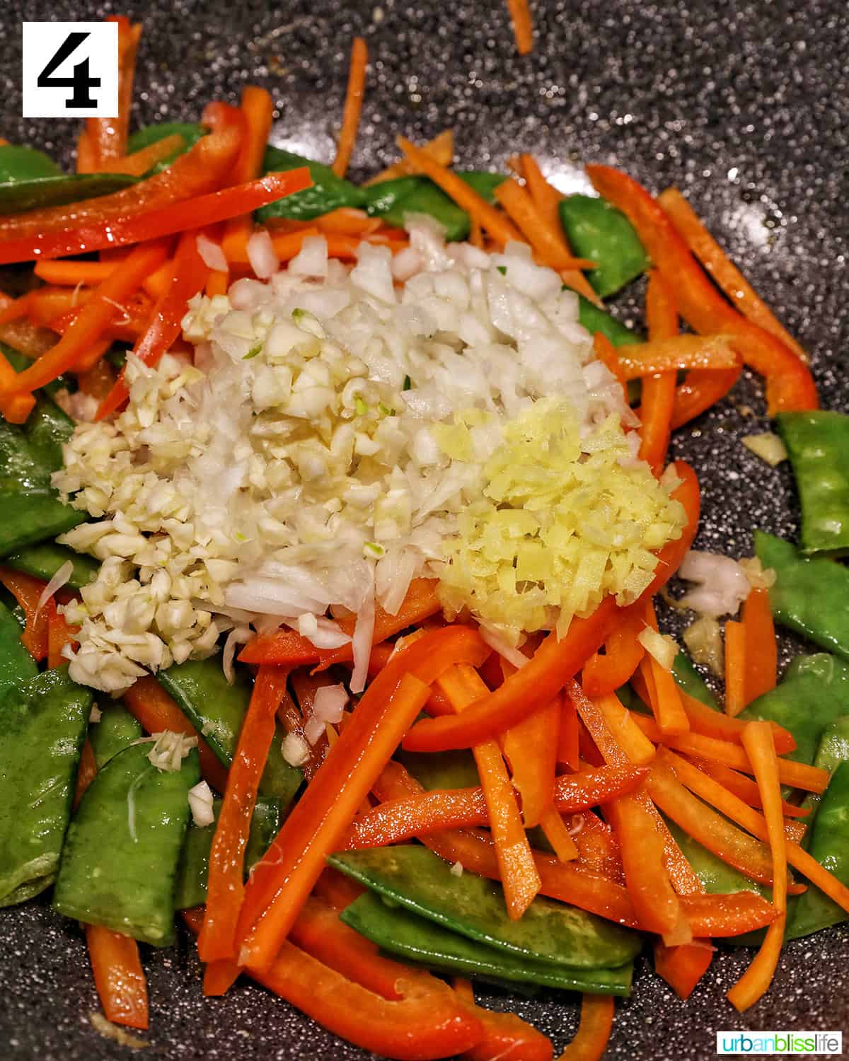 adding diced onions and minced garlic to vegetables in a wok.