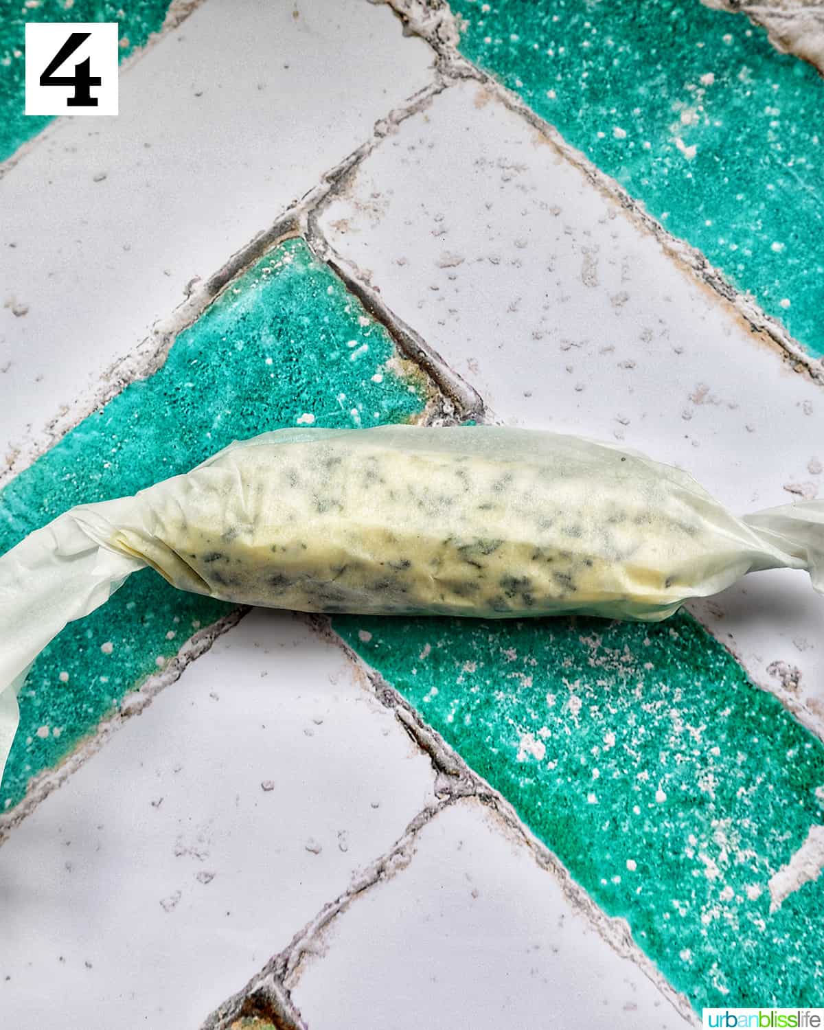 garlic herb compound butter on a green plate with side of herbs.