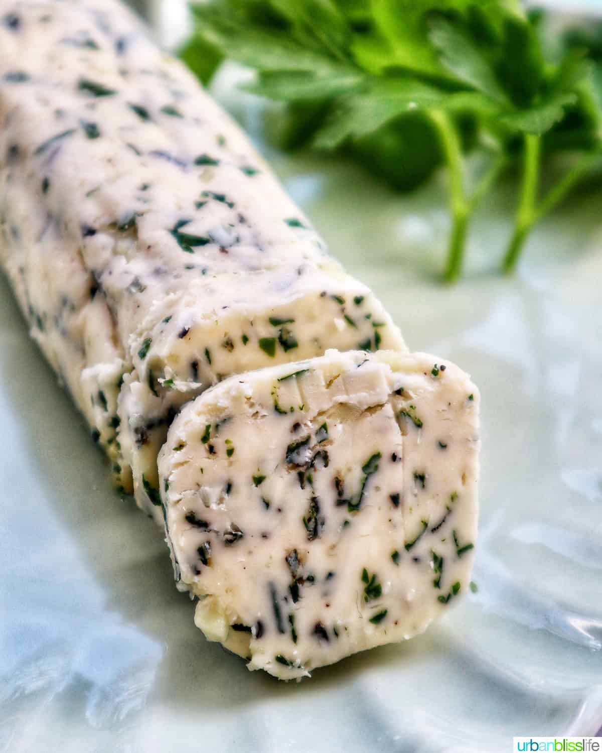 garlic herb compound butter on a green plate with side of herbs.