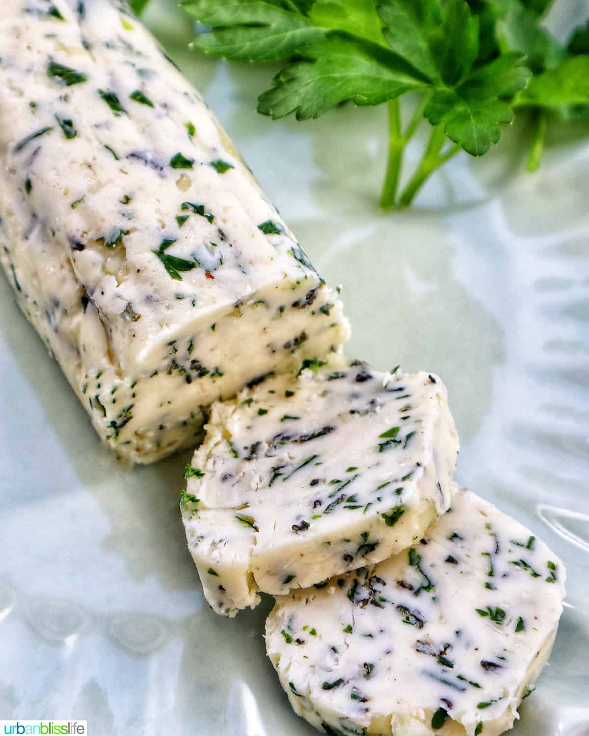 garlic herb compound butter on a green plate with side of herbs.