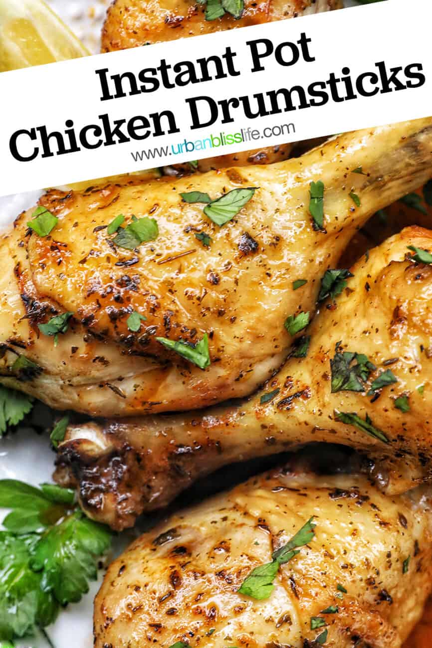 Stack of chicken drumsticks with seasoning and garnished with parsley and side of lemon wedges on bed of herbs.