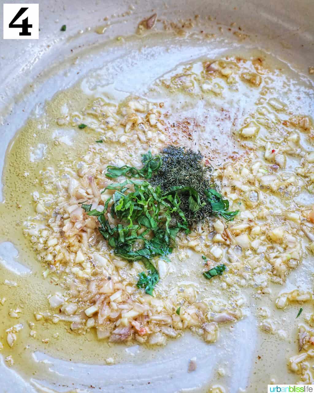 fresh basil and dill added to garlic and shallots in a pan to make lobster ravioli sauce.