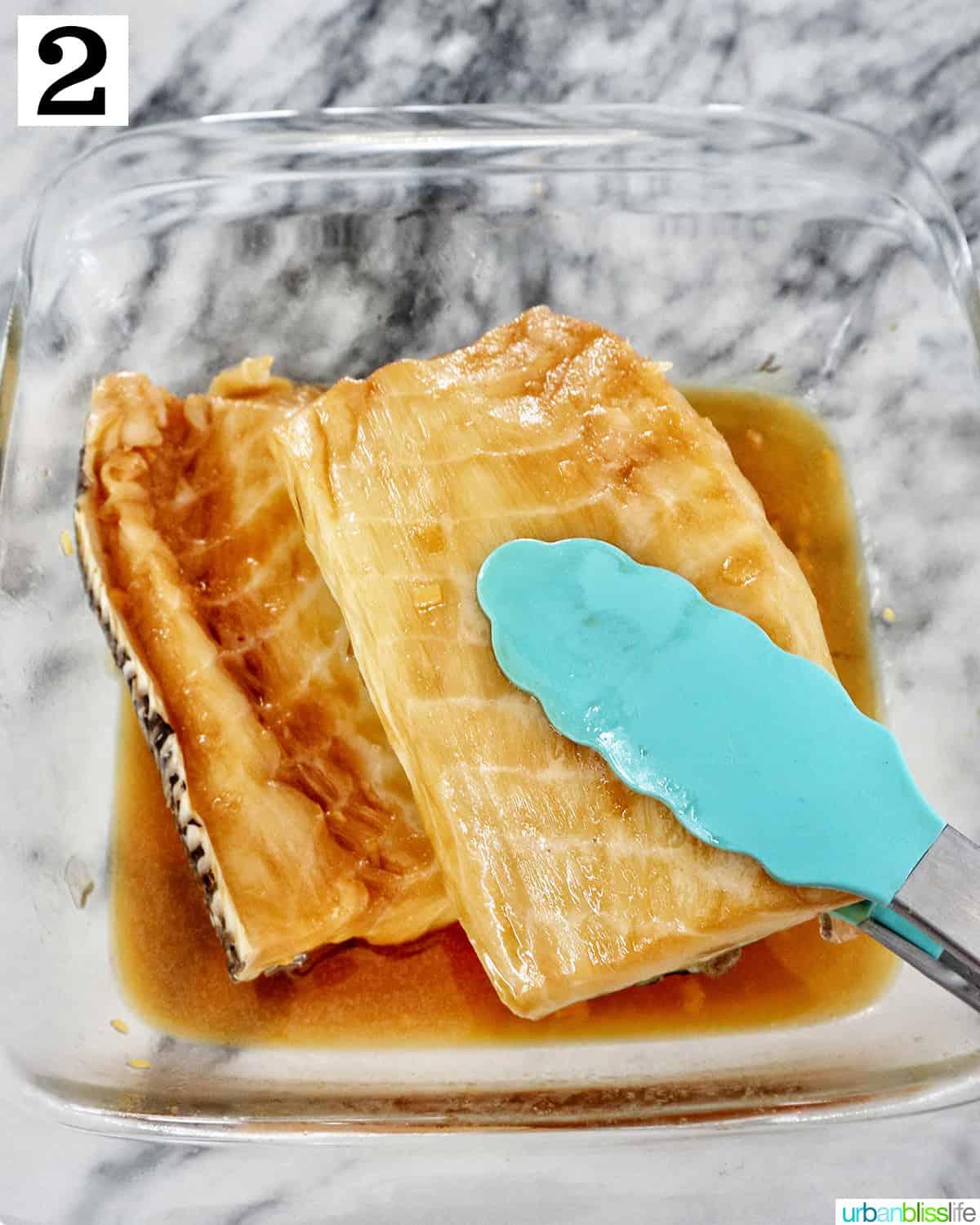 blue tongs flipping sea bass in marinade.