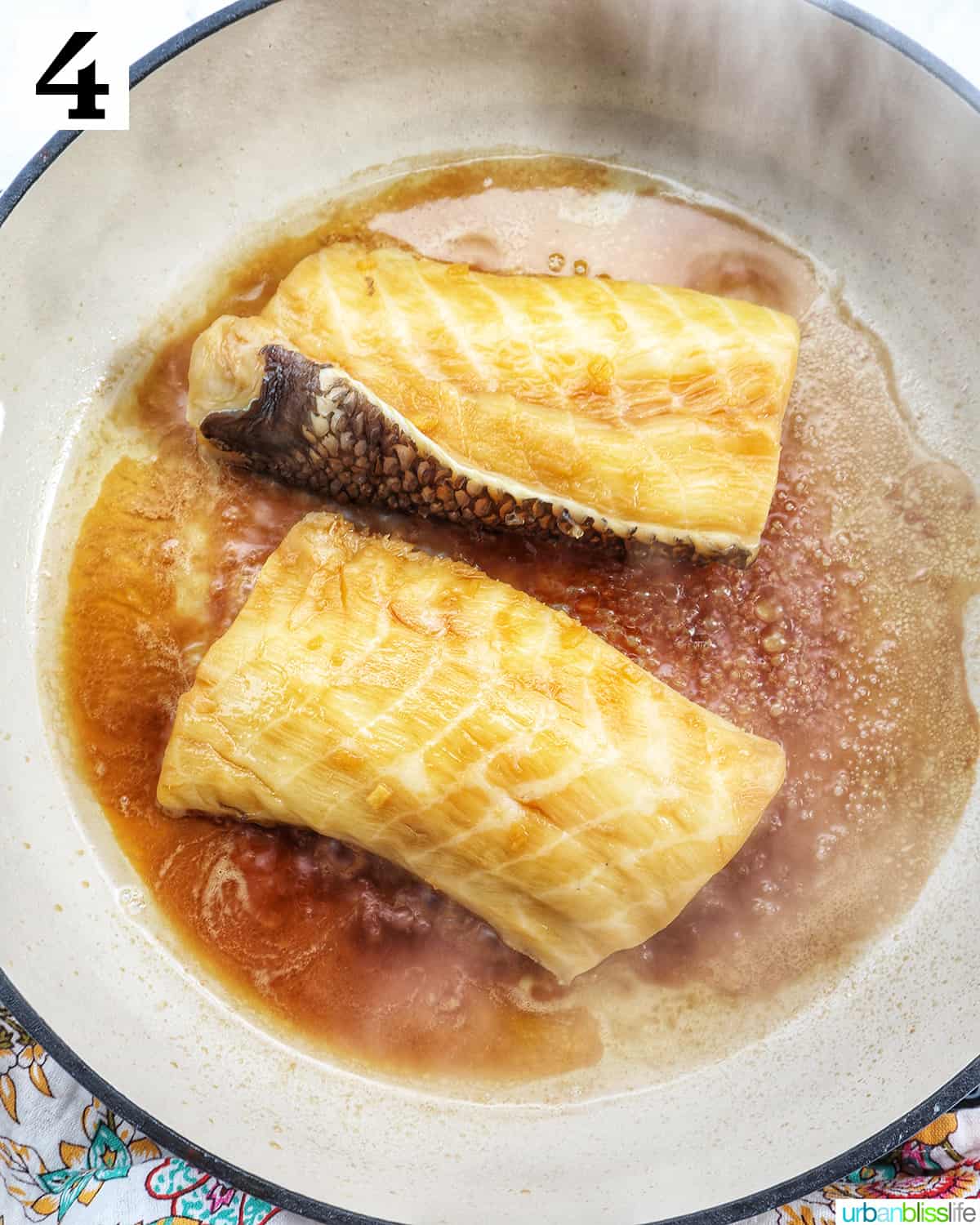 two sea bass fillets in a pan cooking.