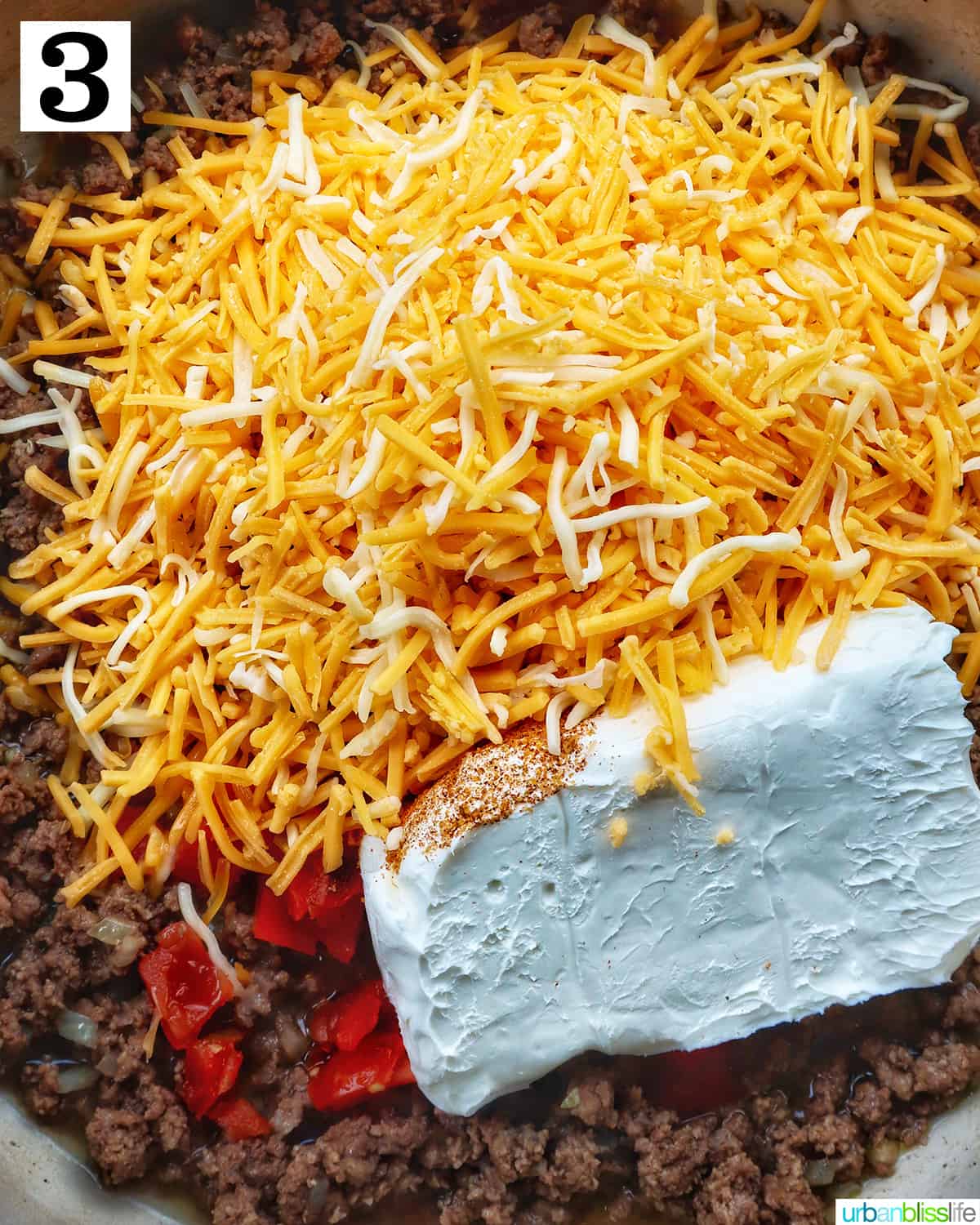 shredded cheese, cream cheese added to ground beef in a pan.