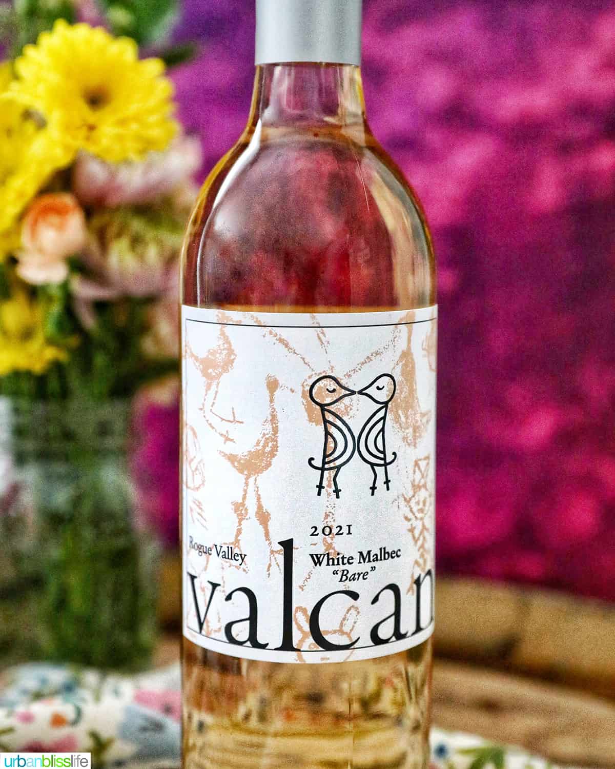 bottle of white malbec on a wine barrel.