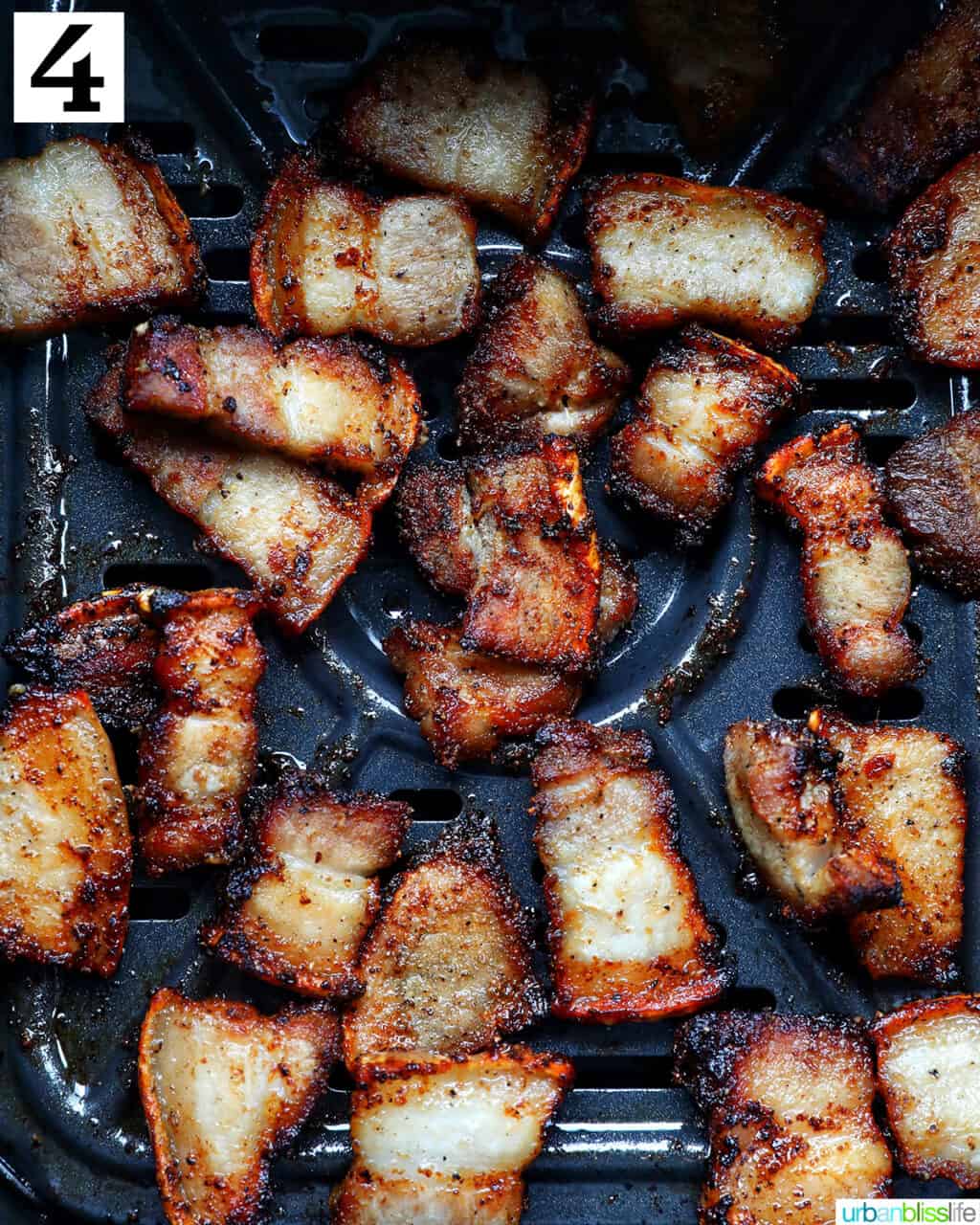 cooked pork belly bites in an air fryer basket.