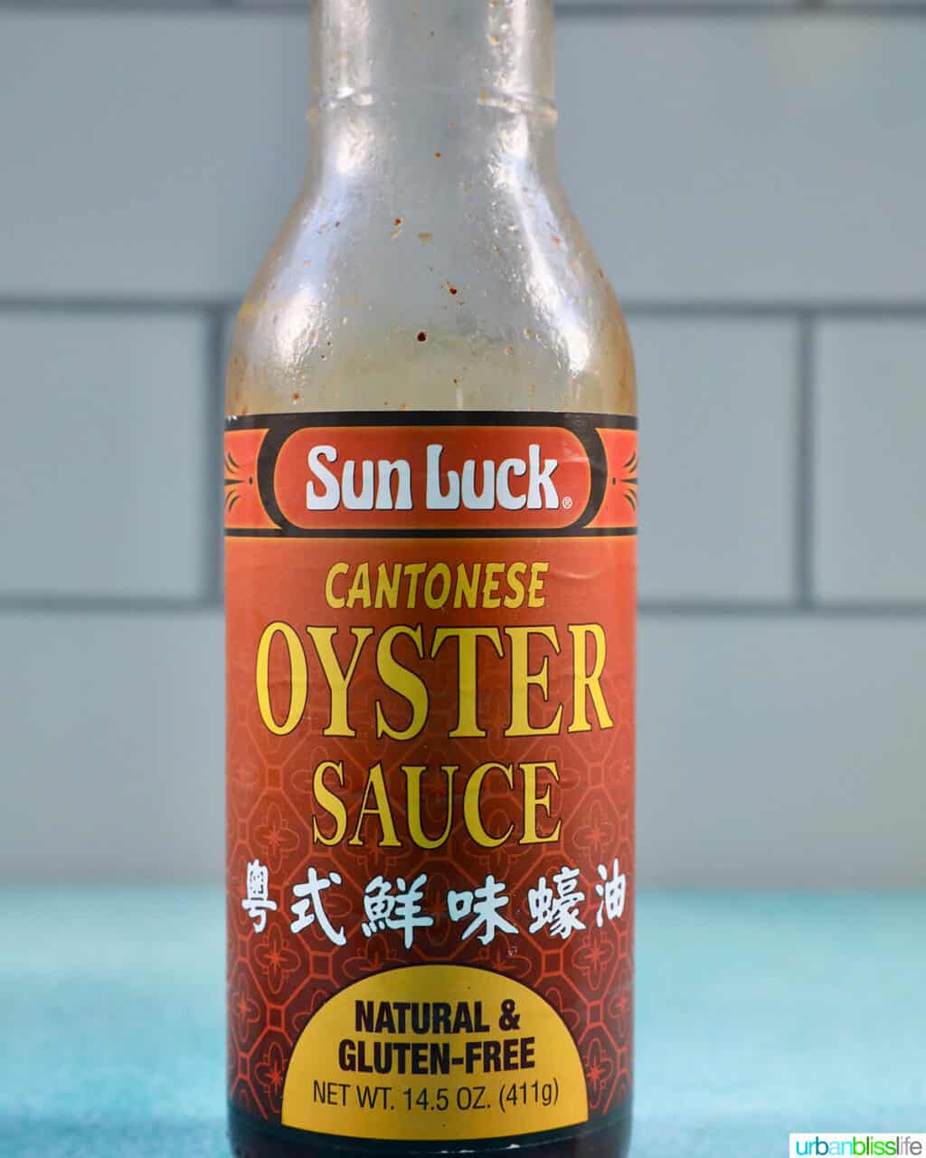 bottle of oyster sauce on a blue table with white tile background.