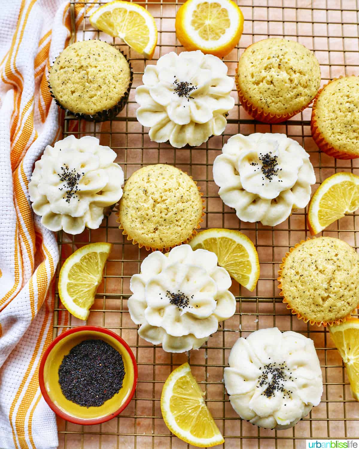 Lemon poppyseed cupcakes undecorated next to cupcakes with buttercream frosting flower decorations next to lemon slices.