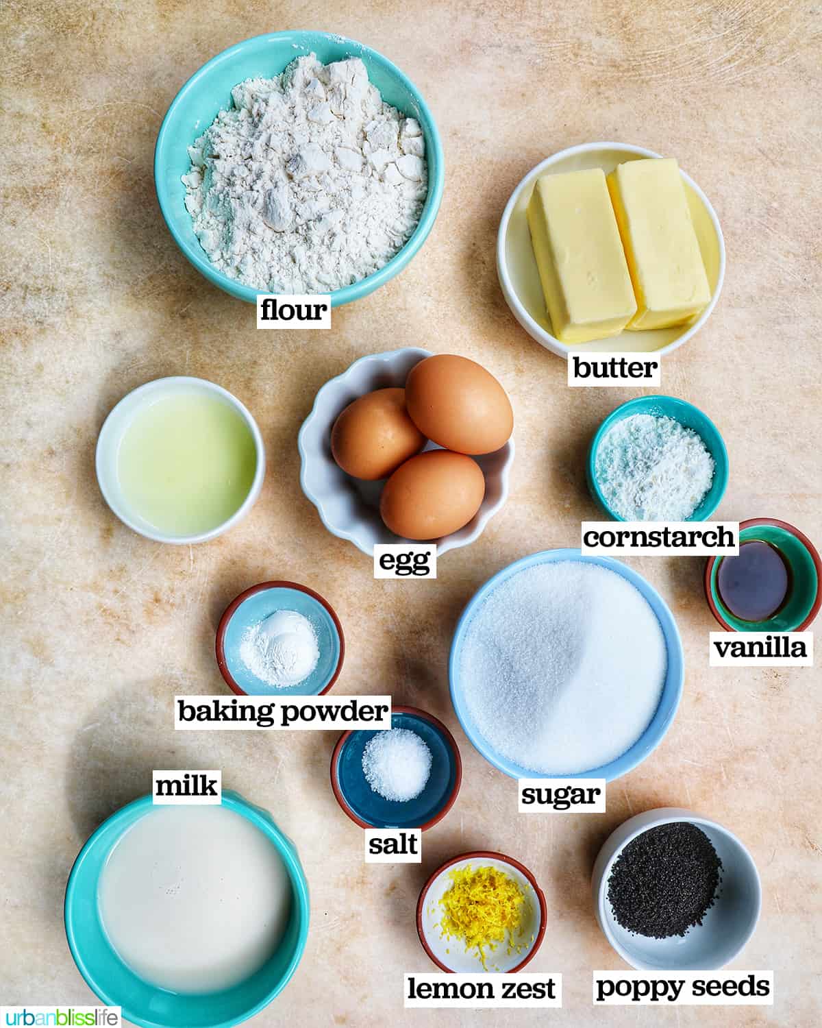 bowls of ingredients to make lemon poppyseed cupcakes on a yellow background.