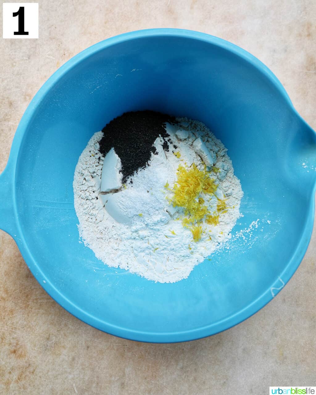 blue bowl with dry ingredients to make lemon poppyseed cupcakes.
