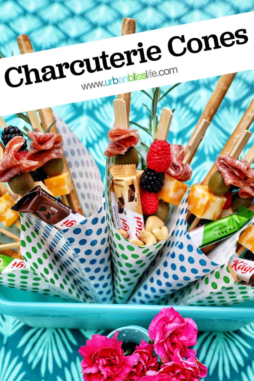 Charcuterie cones with fruit, cheeses, breadsticks, nuts, chocolate, herbs in paper cones with title text that reads "Charcuterie Cones."