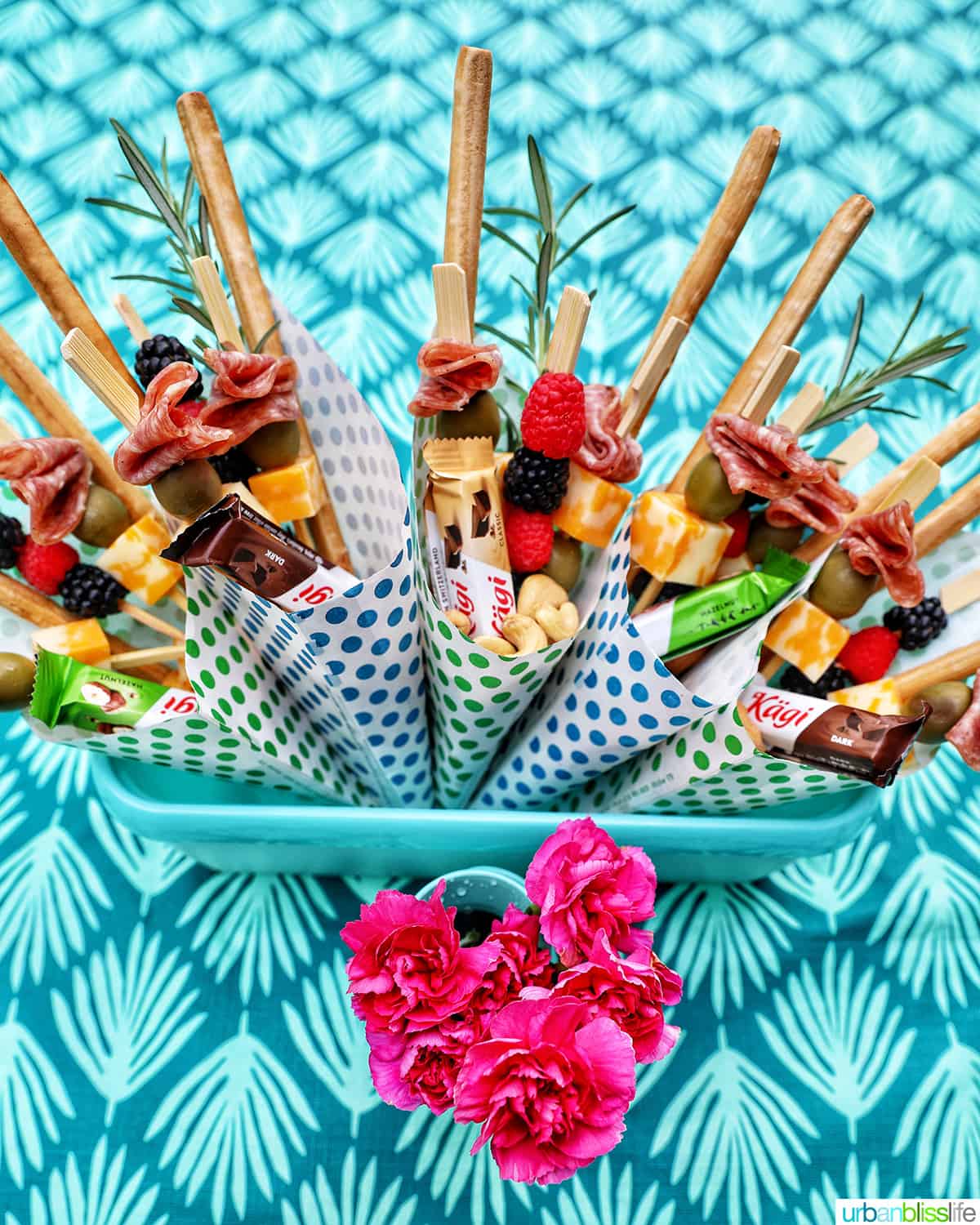 Charcuterie cones with fruit, cheeses, breadsticks, nuts, chocolate, herbs in paper cones.