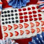 4th of July Fruit Pizza with blueberries, strawberries, raspberries surrounded by red, white, and blue decorations.