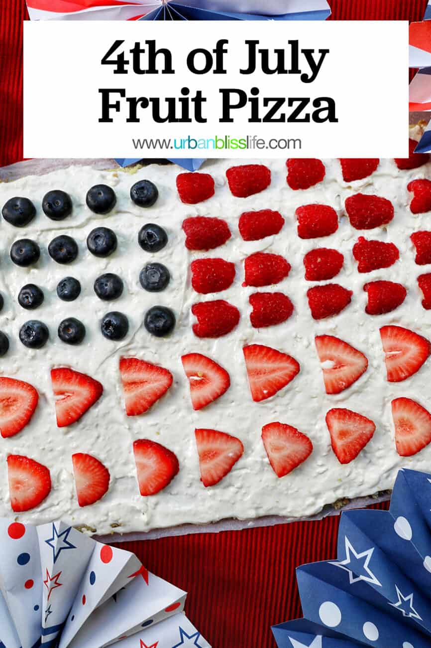 4th of July Fruit Pizza with blueberries, strawberries, raspberries surrounded by red, white, and blue decorations.