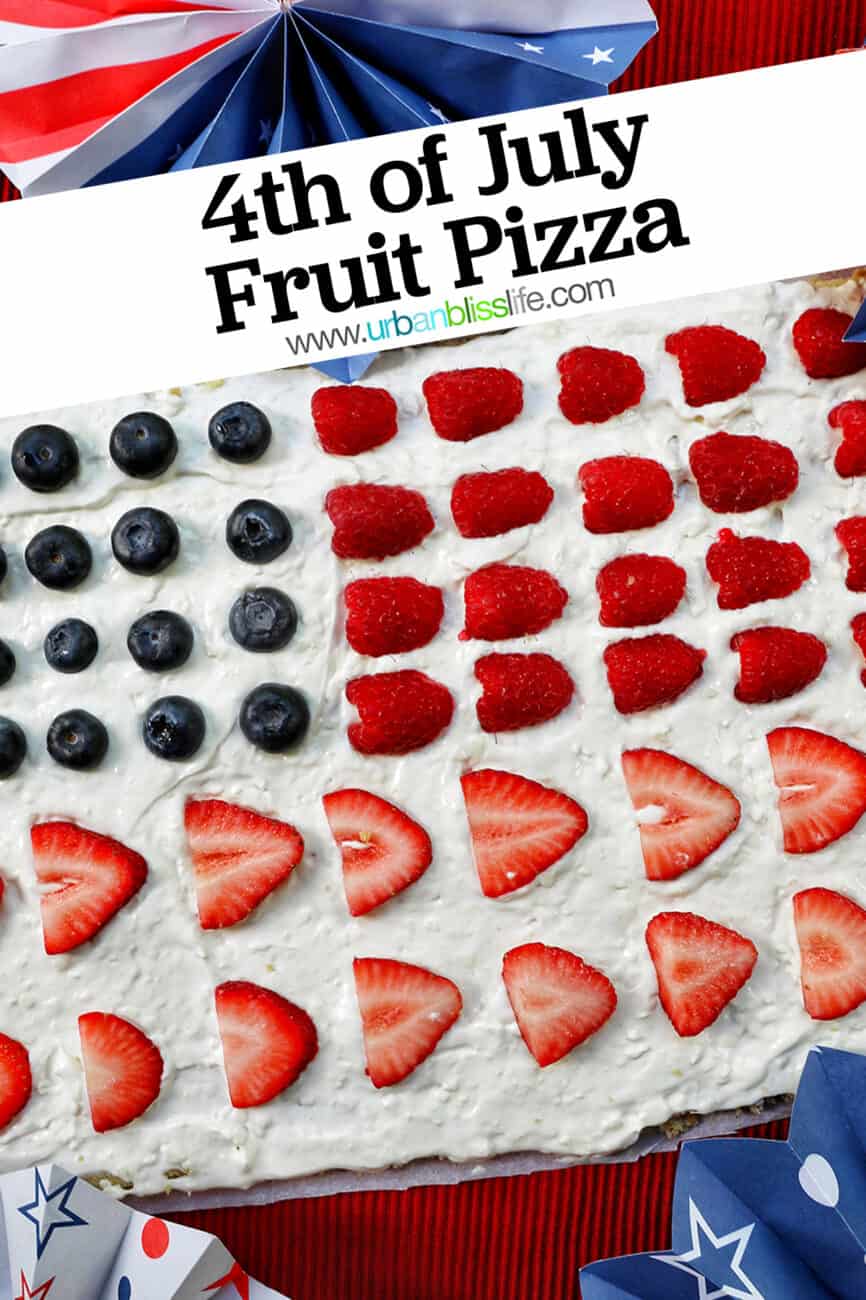 4th of July Fruit Pizza with blueberries, strawberries, raspberries surrounded by red, white, and blue decorations.