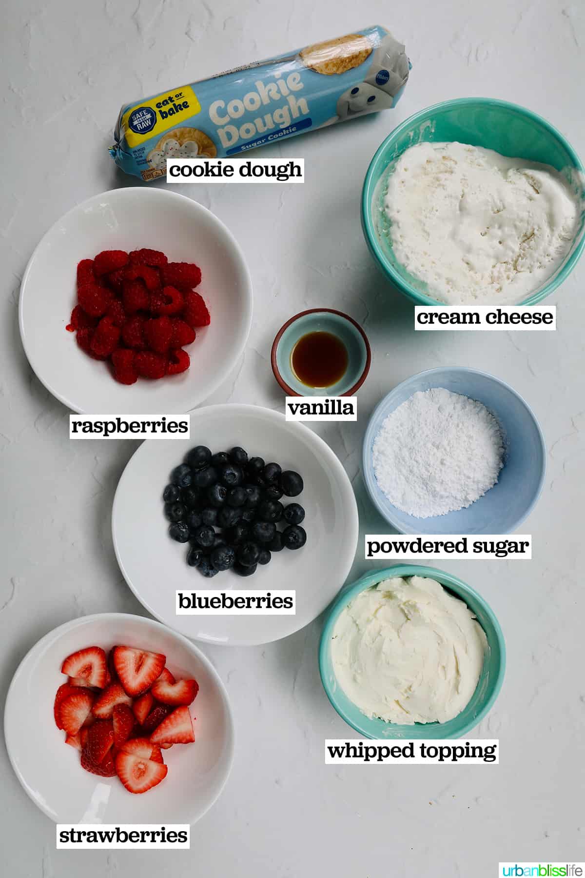 bowls of ingredients - fresh fruit, cream cheese, powdered sugar, sugar cookie dough - to make 4th of July fruit pizza.