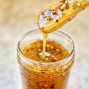 honey spoon lifting hot honey sauce out of a mason jar.
