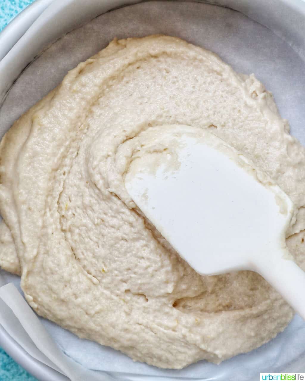 white spatula smoothing out Strawberry Spoon Cake batter in a parchment paper-lined baking pan.