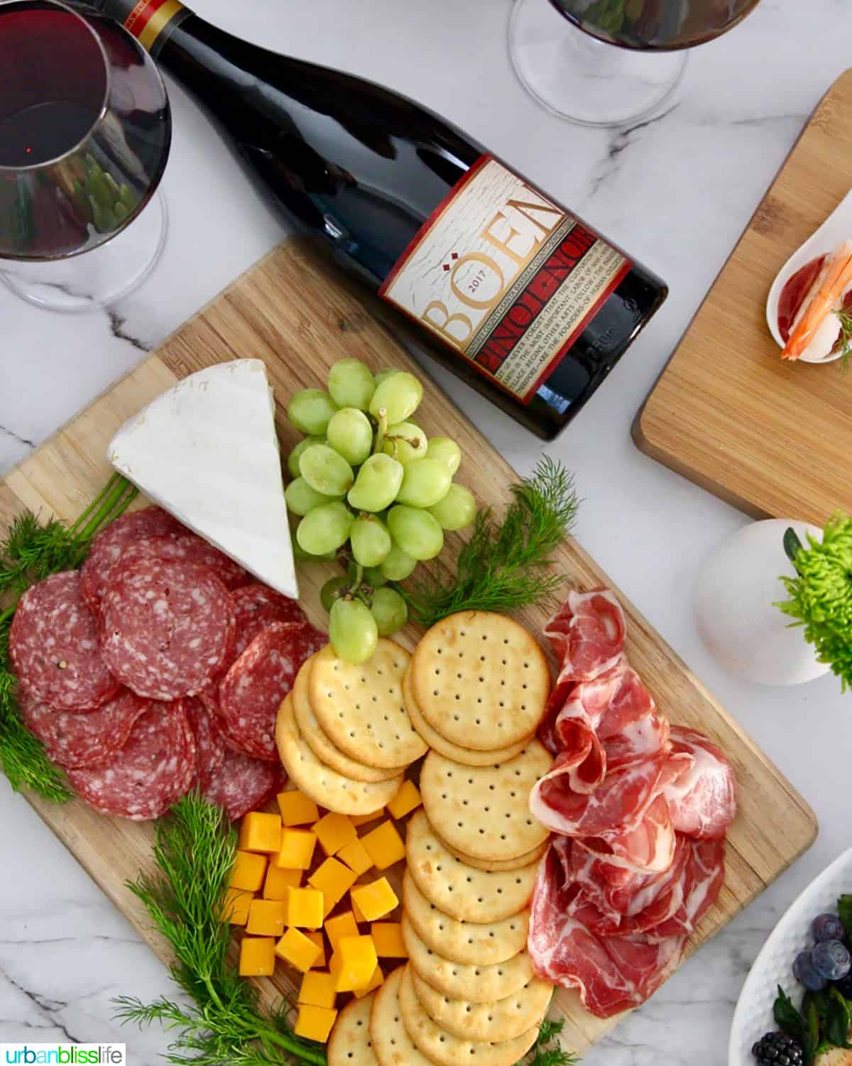 bottle of red wine pinot noir with charcuterie board with meats, cheese, crackers.