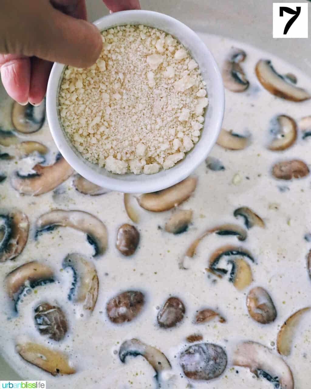sprinkling grated parmesan cheese over chopped mushrooms cooking in a pan.