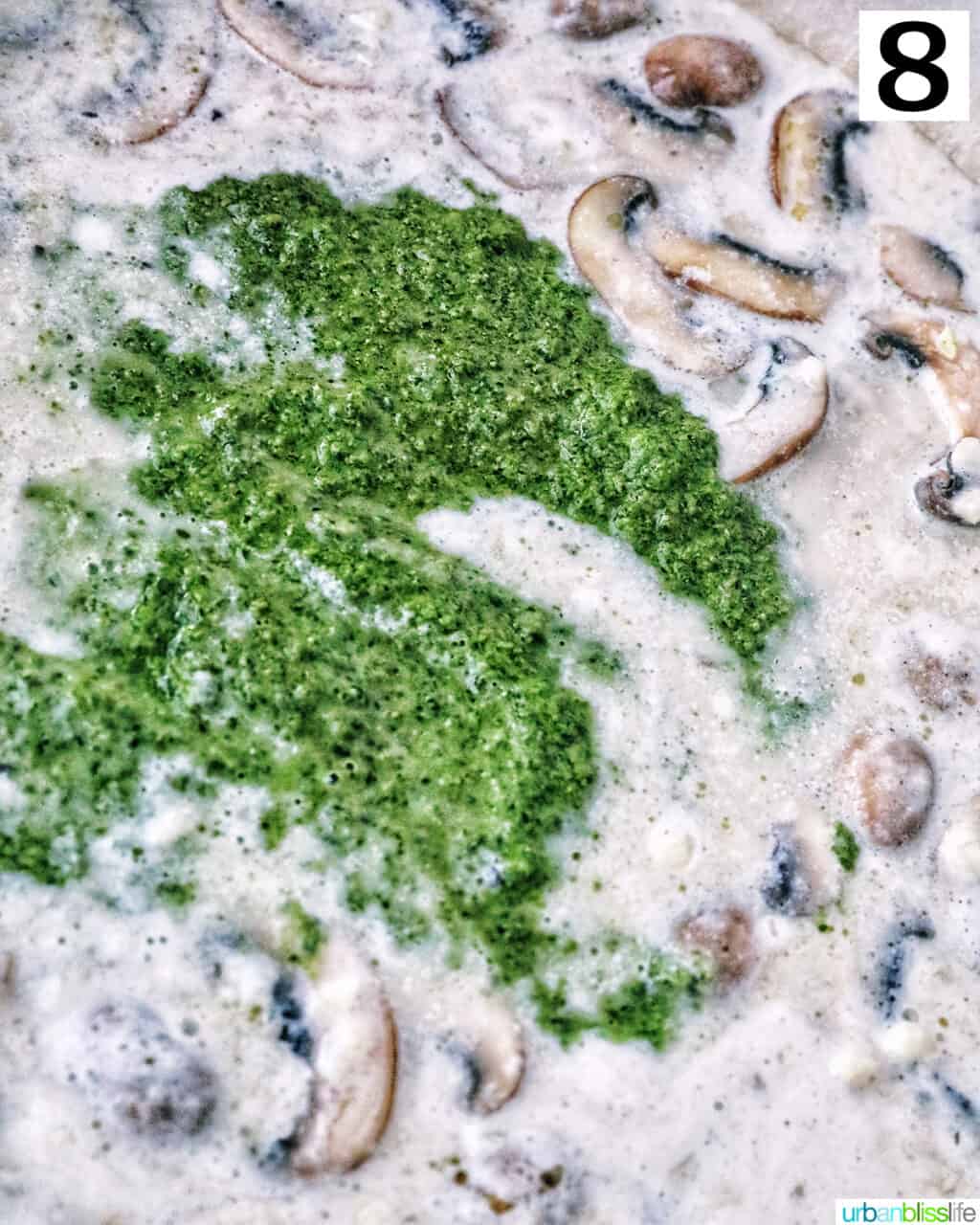 pesto sauce added to mushroom cream sauce in a pan.