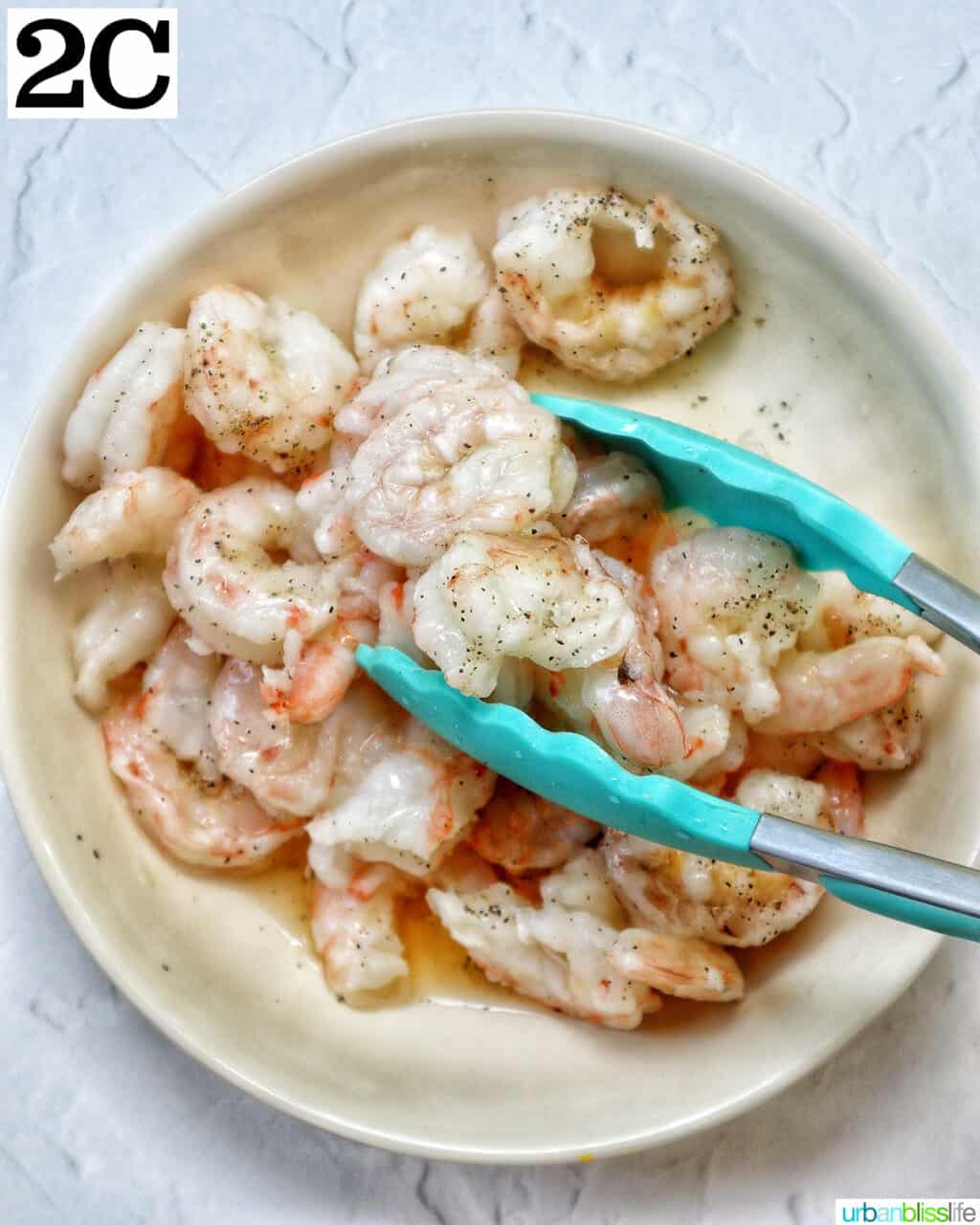 tongs in a bowl of prawns.