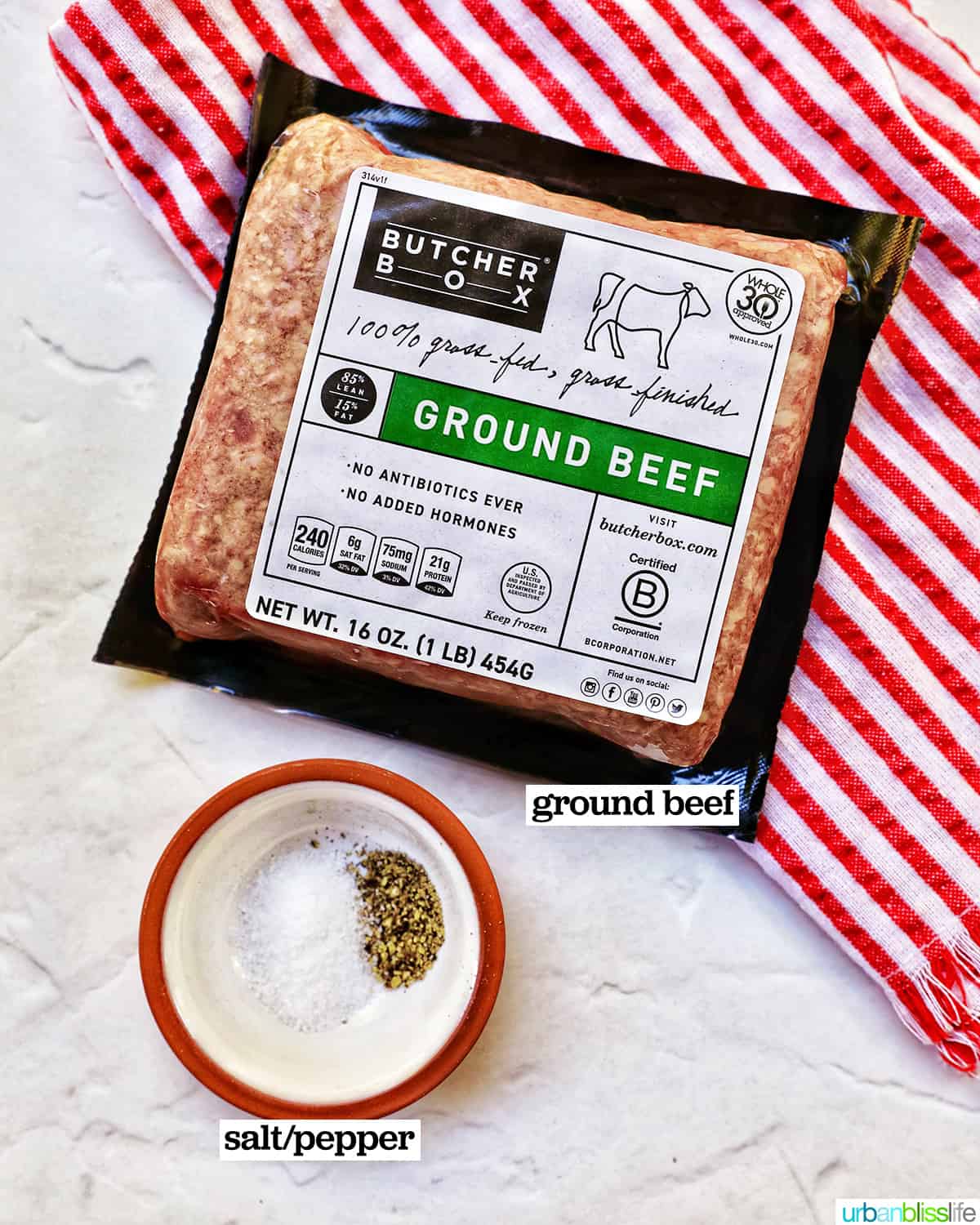 package of ground beef on a red and white striped towel and a small bowl of salt and pepper.