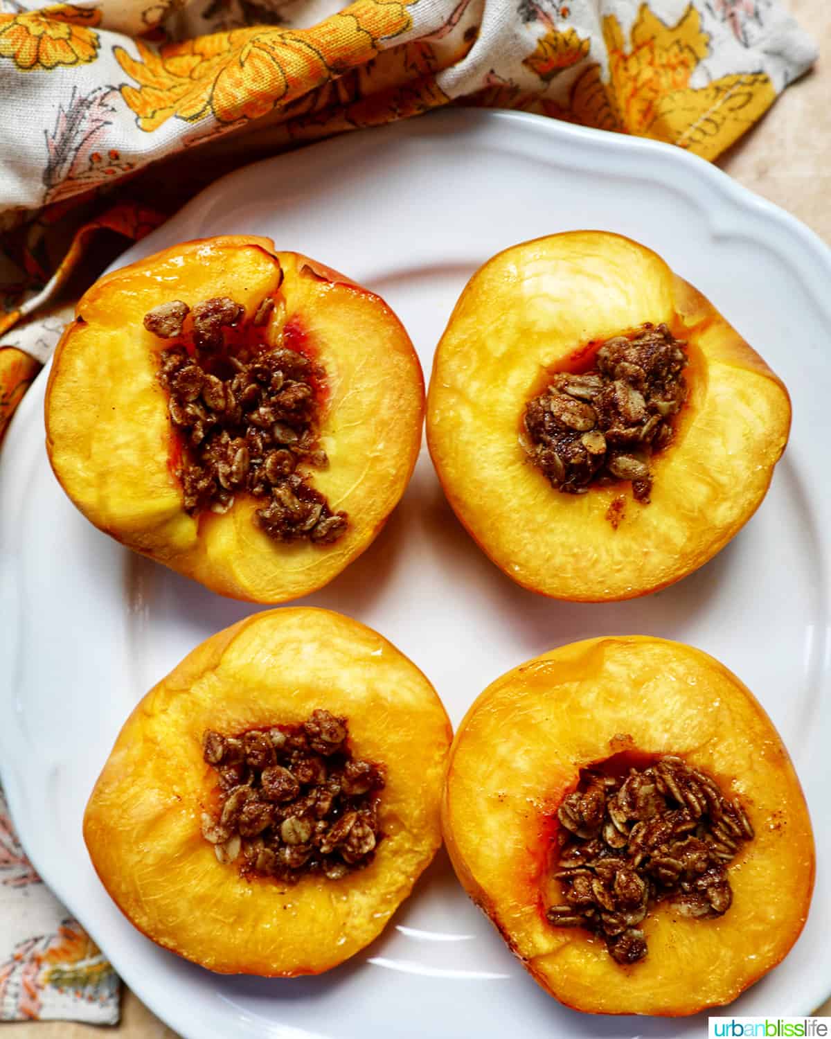 halved peaches with cinnamon oats topping on a white plate.