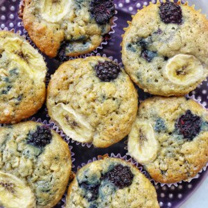 purple plate with several banana blackberry oatmeal muffins on top.
