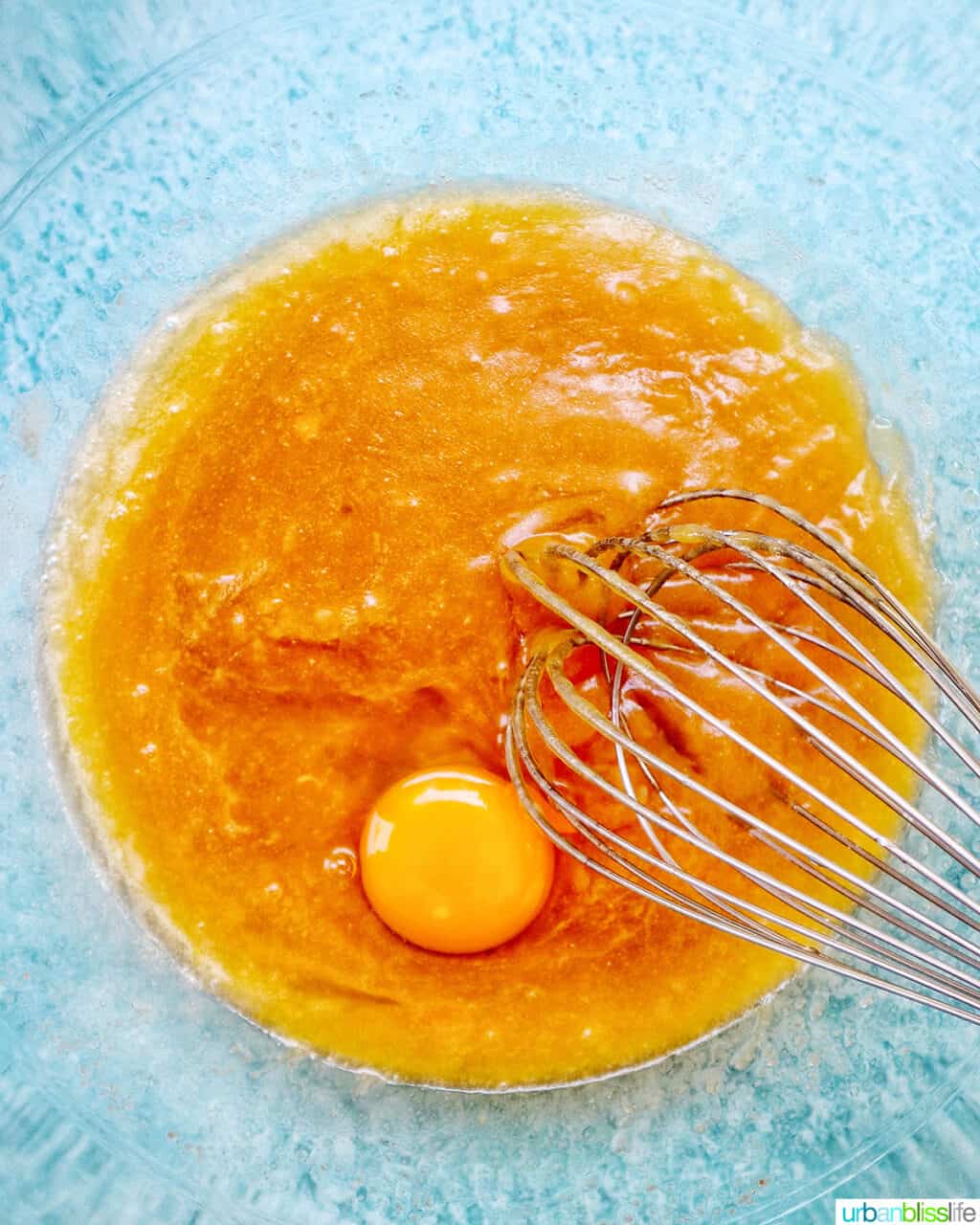 whisk in a clear mixing bowl with wet ingredients and egg yolk.