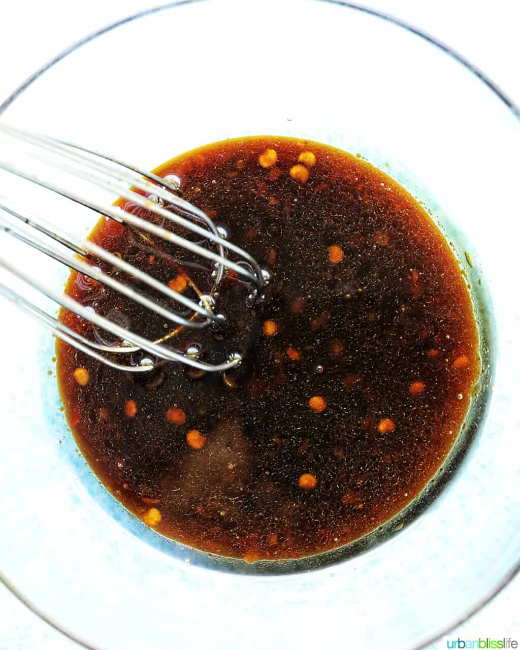 large bowl with chili garlic noodles sauce and a whisk.