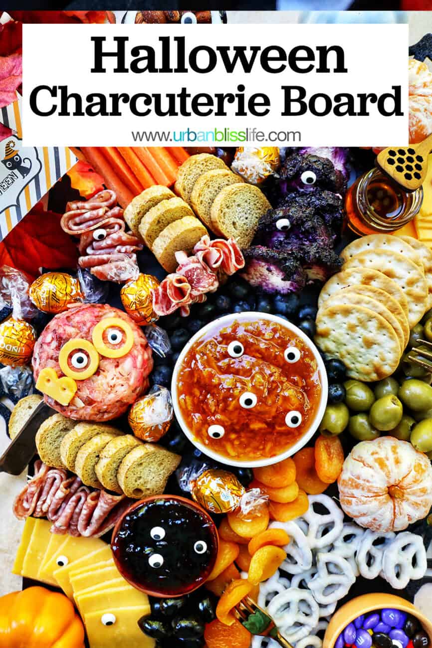 Halloween Charcuterie Board with charcuterie meats, cheeses, crackers, jams, pretzels, fruits, candy eyes, and more orange, purple, and black food with title text.