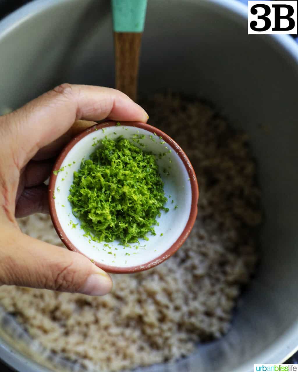 hand holding a bowl of lime zest over brown rice in an instant pot.