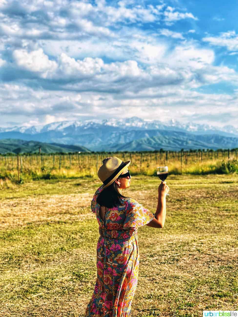 Marlynn Jayme Schotland holding a glass of Kazakhstan wine at Arba Winery with the Tian Shan mountains in the background.