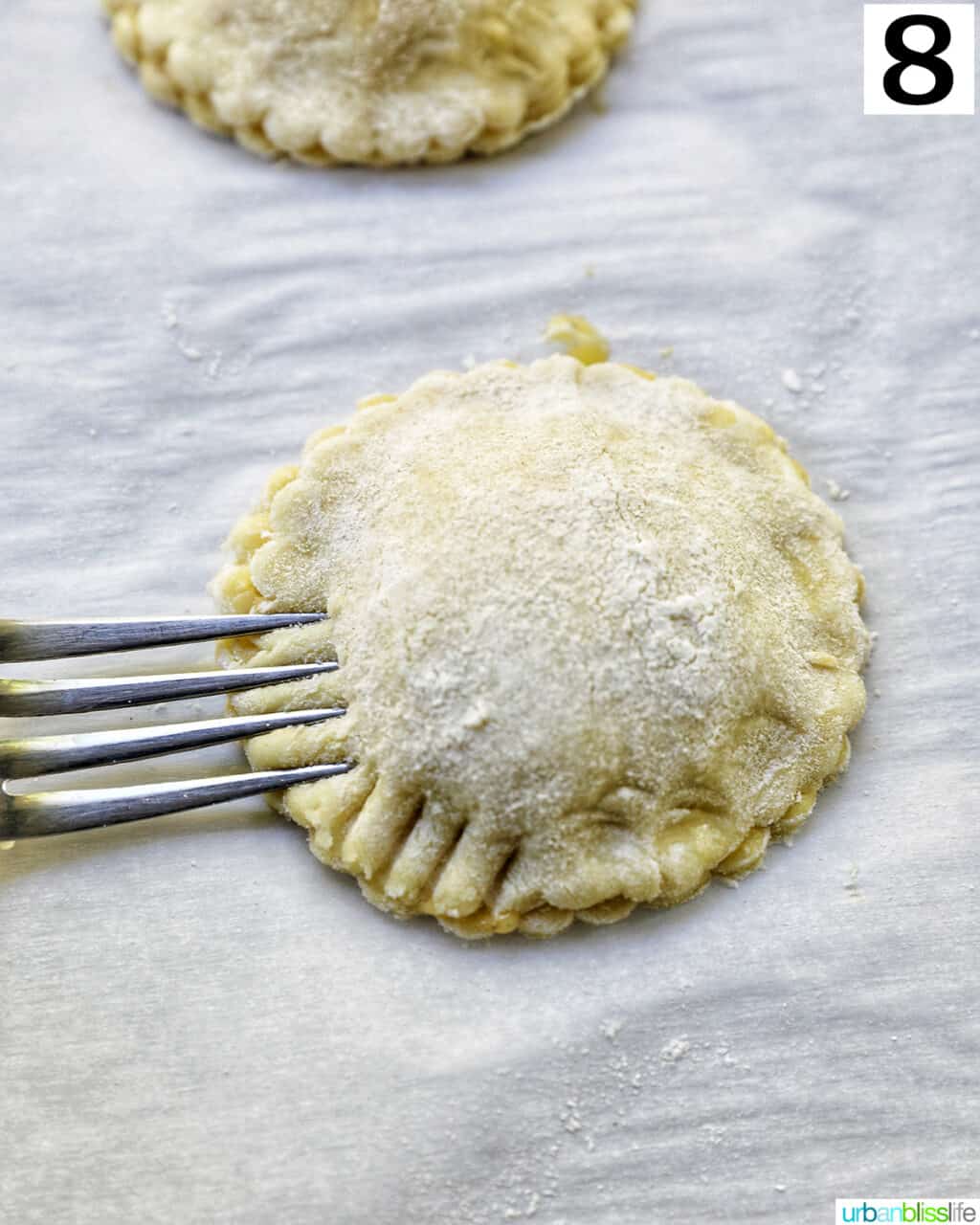 fork pressing into the sides of a peach mango pie.