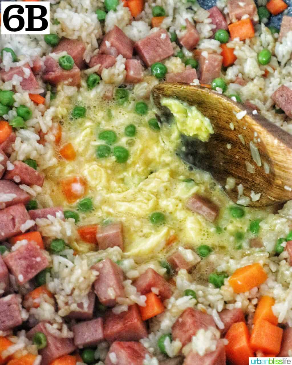 wooden spoon scrambling eggs for spam fried rice.