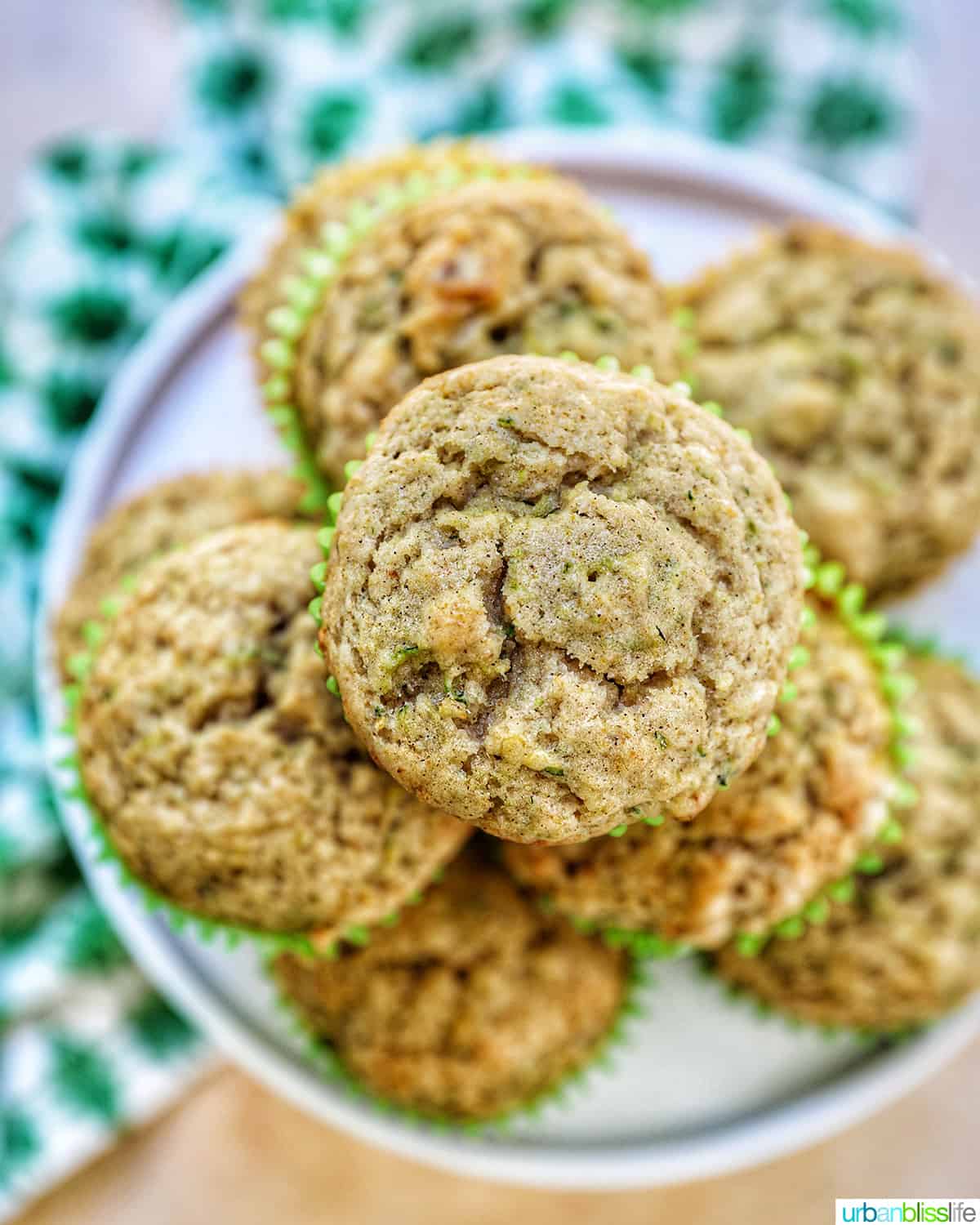 vegan zucchini muffins stacked on top of each other on a white plate.