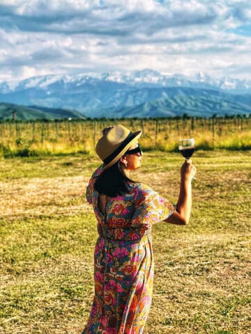 Marlynn Jayme Schotland holding a glass of Kazakhstan wine at Arba Winery with the Tian Shan mountains in the background.