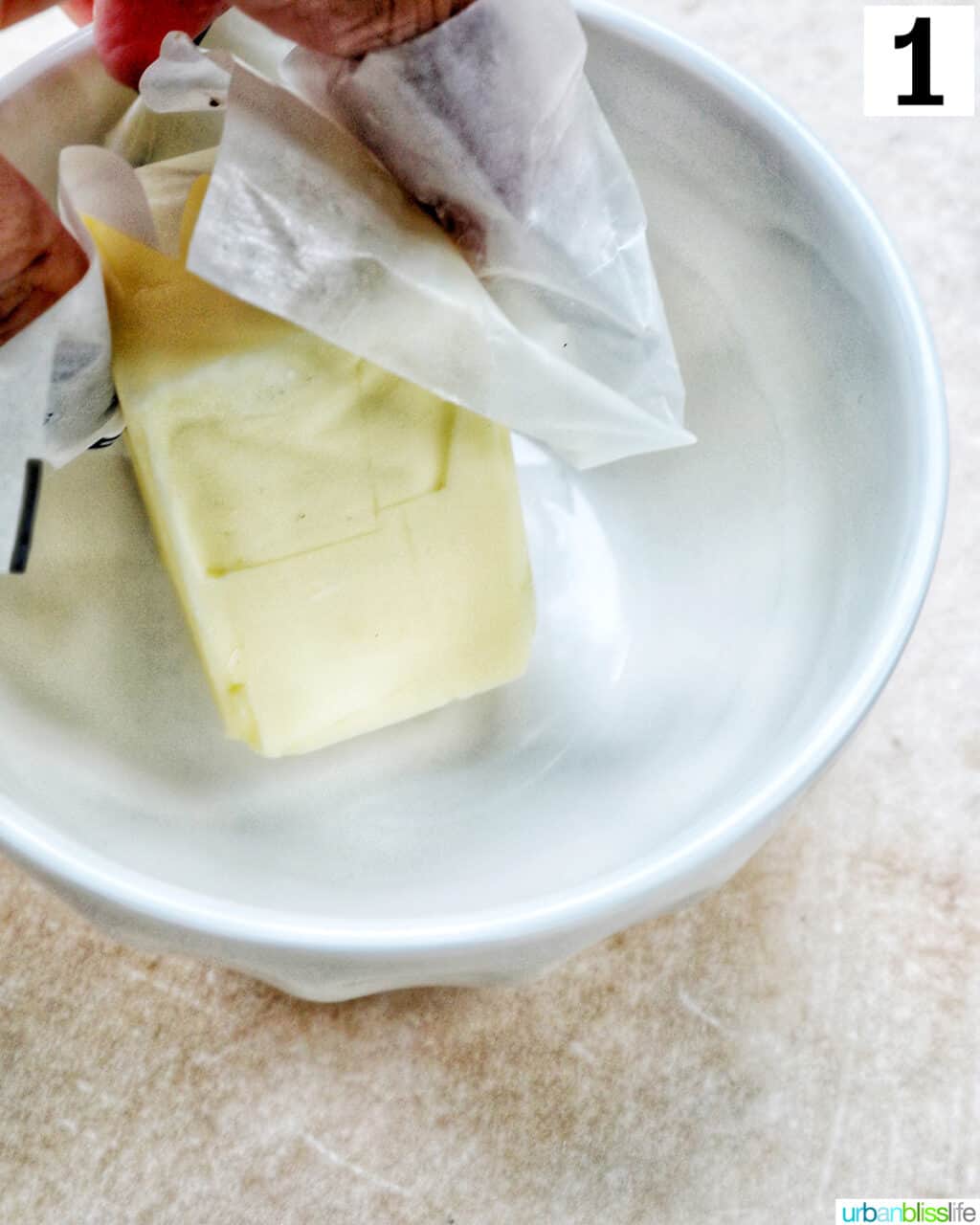 hand greasing a bowl with butter.