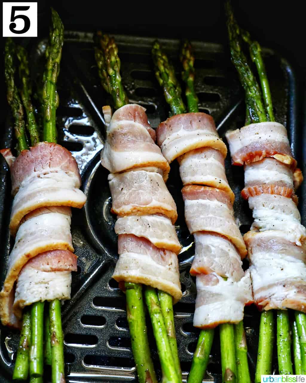 bacon wrapped asparagus in an air fryer basket.